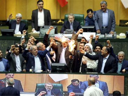 Iranian lawmakers burn two pieces of papers representing the U.S. flag and the nuclear dea