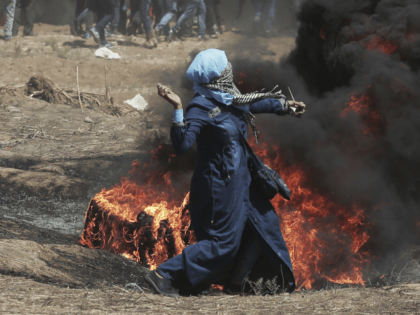 A Palestinian woman hurls stones towards Israeli troops during a protest at the Gaza Strip's border with Israel, Monday, May 14, 2018. Israeli fire has killed dozens of Palestinians during mass protests along the Gaza border, marking the deadliest day of violence since a devastating 2014 cross-border war and casting …