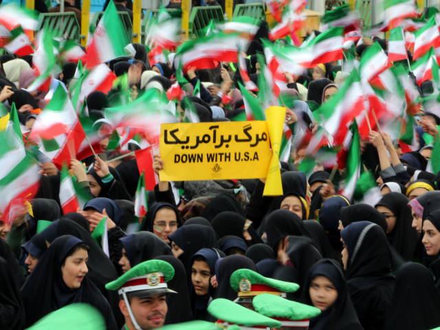 Iranian schoolgirls wave their national flag and hold an anti-US slogan during celebration