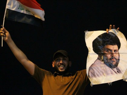 An Iraqi man celebrates with a picture of Shiite cleric Muqtada Sadr during the general election in Baghdad on May 14, 2018. - The race to become Iraq's next prime minister appeared wide open as two outsider alliances looked to be in the lead after the first elections since the …
