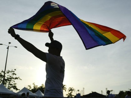 A man holds up a rainbow flag at the end of the annual Gay Pride parade in Panama City, Saturday, July, 1, 2017. . (AP Photo/Arnulfo Franco)