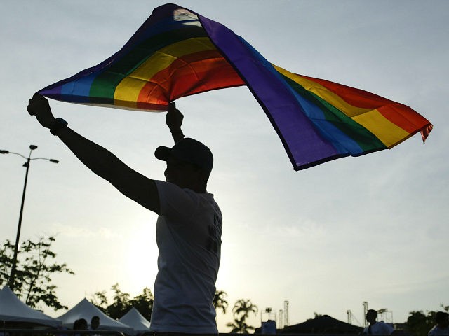 A man holds up a rainbow flag at the end of the annual Gay Pride parade in Panama City, Sa