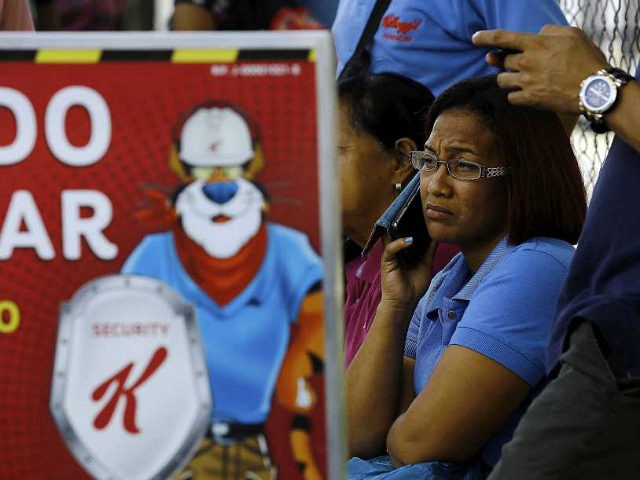 Workers wait for information about their jobs outside the Kellogg's factory in Maracay, Ve