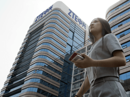 In this May 8, 2018, photo, a woman pass by a ZTE building in Beijing, China. President Donald Trump's weekend social media musings about China injected new uncertainty into the Washington's punishment of Chinese tech giant ZTE and planned trade talks between the two countries. (AP Photo/Ng Han Guan)