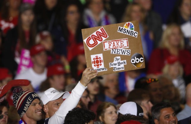 An audience member holds a fake news sign during a President Donald Trump campaign rally in Washington Township, Mich., Saturday, April 28, 2018. (AP Photo/Paul Sancya)