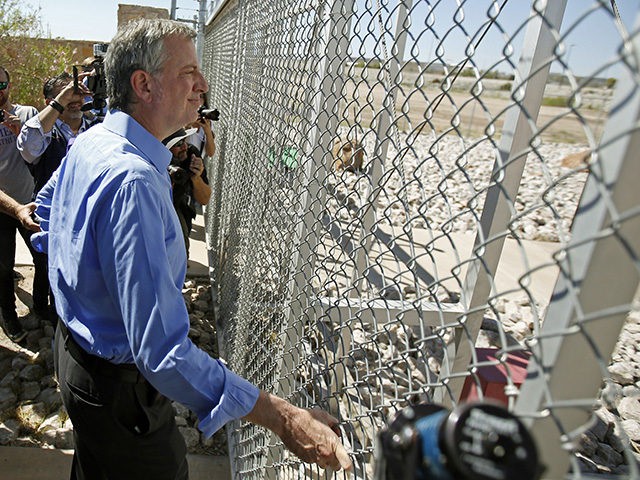 New York City Mayor Bill de Blasio looks through the fence towards the holding facility fo