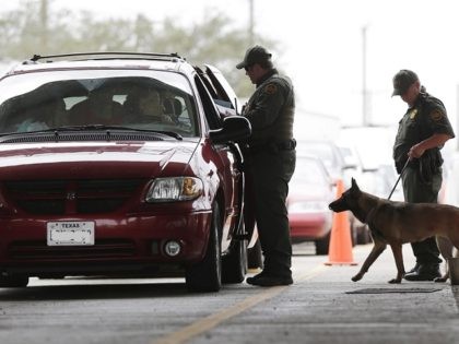 U.S. Customs and Border Patrol agents and K-9 security dog keep watch at a checkpoint station, on Feb. 22, 2013, in Falfurrias, Texas. Some drug smugglers caught at the highway checkpoint about an hour north of the Texas-Mexico border are losing their drugs, but not facing prosecution because cooperation between …