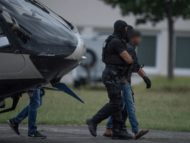 Police officers of a special unit escort Iraqi asylum seeker Ali Bashar, who is suspected of having killed a German teenage girl, from a helicopter to the police headquarters in Wiesbaden, western Germany, after he was flown back from Erbil to Germany on June 9, 2018. - The 20-year-old man …