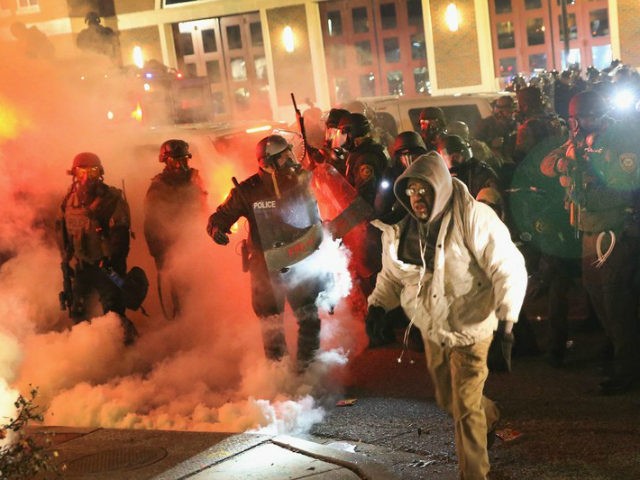 Police guard the Ferguson police department as rioting erupts following the grand jury ann