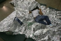 MCALLEN, TX - SEPTEMBER 08: A girl from Central America rests on thermal blankets at a detention facility run by the U.S. Border Patrol on September 8, 2014 in McAllen, Texas. The Border Patrol opened the holding center to temporarily house the children after tens of thousands of families and …