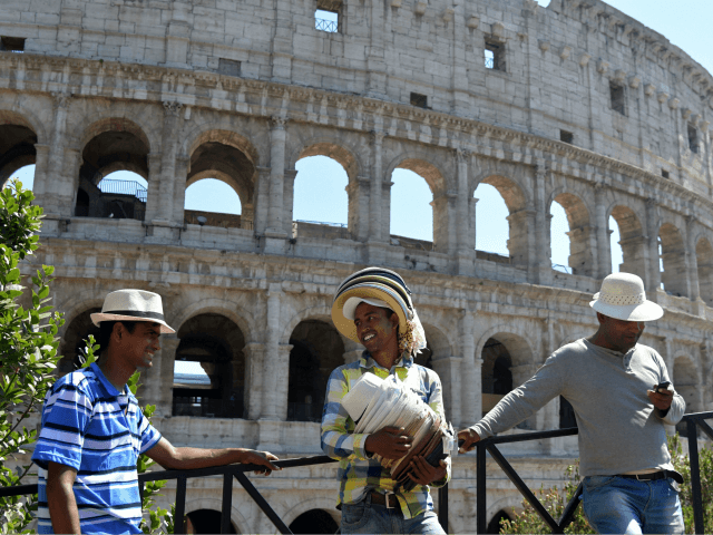 Street vendors wait for tourists to sell hats near the Colosseum on June 21, 2017 in Rome.