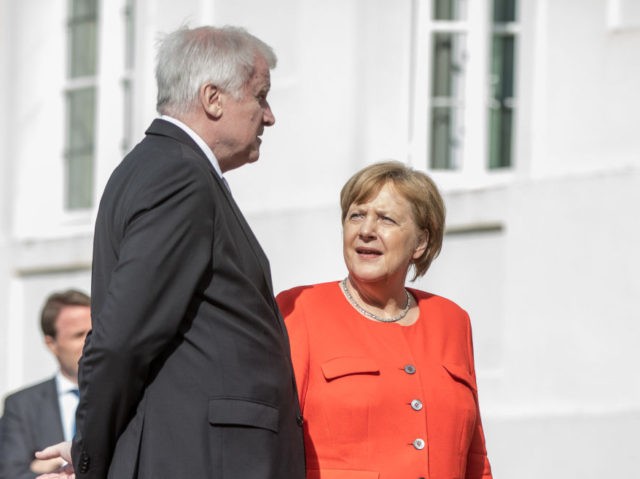 German Interior Minister Horst Seehofer (L) talks with Chancellor Angela Merkel as they ar