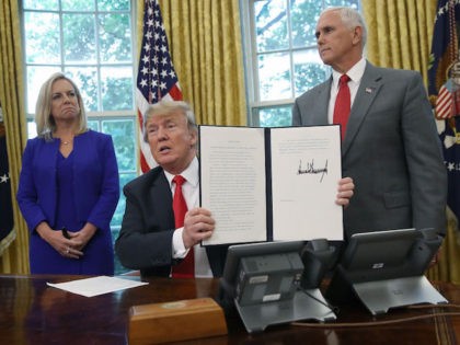 WASHINGTON, DC - JUNE 20: U.S. President Donald Trump, accompanied by Department of Homeland Security Secretary Kirstjen Nielsen (L) and U.S. Vice President Mike Pence (R), displays an executive order he signed that will end the practice of separating family members who are apprehended while illegally entering the United States …