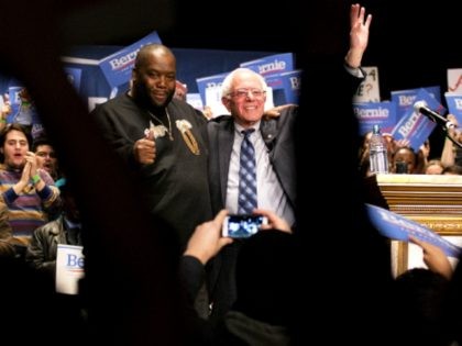 Democratic presidential candidate Sen. Bernie Sanders, I-Vt., right, waves to the crowd while standing with rapper Killer Mike after speaking onstage at a campaign event at the Fox Theatre Monday, Nov. 23, 2015, in Atlanta. (AP Photo/David Goldman)