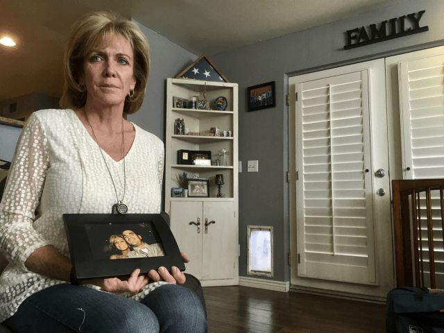 Mary Ann Mendoza poses for a photograph while holding a framed picture of herself and her son, Brandon Mendoza, on Thursday, March 2, 2017, at her home in Mesa, Ariz. Families who have lost loved ones to crimes committed by immigrants are praising President Donald Trump’s announcement this week that …