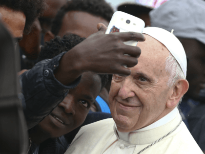 Pope Francis poses for a selfie with a man as he visits a migrant reception centre during