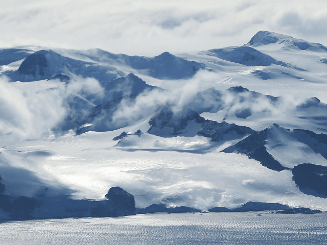 Mountains stand near the coast of West Antarctica as seen from a window of a NASA Operation IceBridge airplane on October 27, 2016 in-flight over Antarctica. NASA's Operation IceBridge has been studying how polar ice has evolved over the past eight years and is currently flying a set of 12-hour …