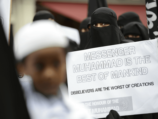 Muslim protesters hold signs as they demonstrate against a French magazine that published nude cartoons of the Prophet Mohammed outside the French embassy in London on September 21, 2012. Around 100 protesters shouted slogans outside the French embassy in London over the cartoons at the same time as violent demonstrations continue in parts of the Muslim world over a US-made film that mocked the Prophet Mohammed. AFP PHOTO / ADRIAN DENNIS (Photo credit should read ADRIAN DENNIS/AFP/GettyImages)