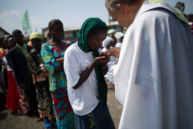 A Congolese woman takes communion at an open-air church service where thousands of interna