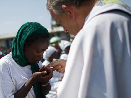 A Congolese woman takes communion at an open-air church service where thousands of interna