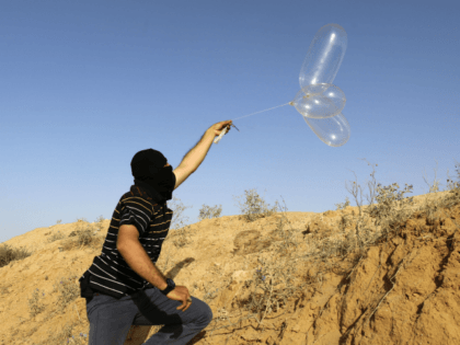 A masked Palestinian launches a Balloon loaded with flammable materials to be flown toward Israel, at the Israel-Gaza border, in Rafah in the southern Gaza Strip on June 17, 2018. (Photo by SAID KHATIB / AFP) (Photo credit should read SAID KHATIB/AFP/Getty Images)
