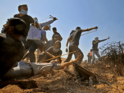 Hamas Palestinian protesters use slingshots to hurl stones toward Israeli forces during cl