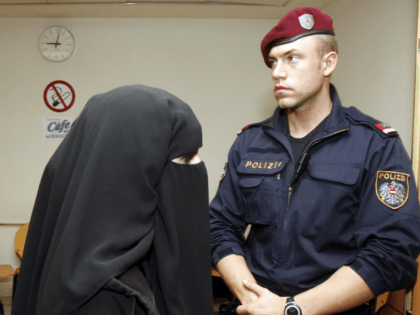 Mona S., left, wife of terror suspect Mohamed M., unseen, is accompanied by a police man as she enters the court room prior to the start of the Austrian terror trial at court in Vienna, Austria, on Thursday, Nov. 13, 2008. The Muslim couple convicted of making online terrorism threats …