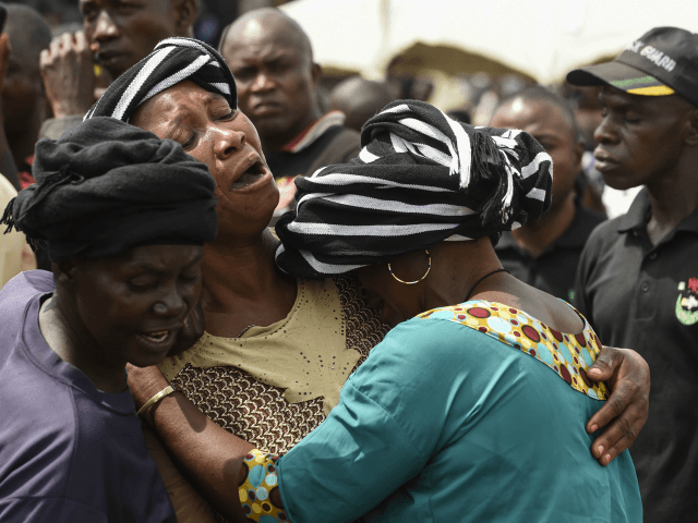 A woman cries while trying to console a woman who lost her husband during the funeral serv