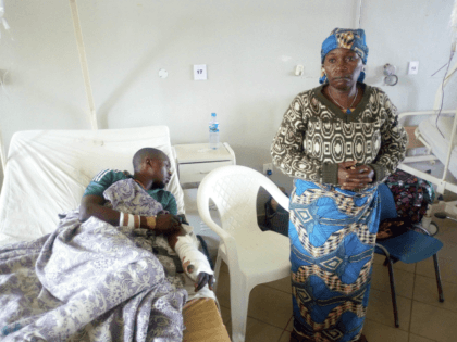 A woman stands near her relative as he receives treatment at the Jos University teaching h