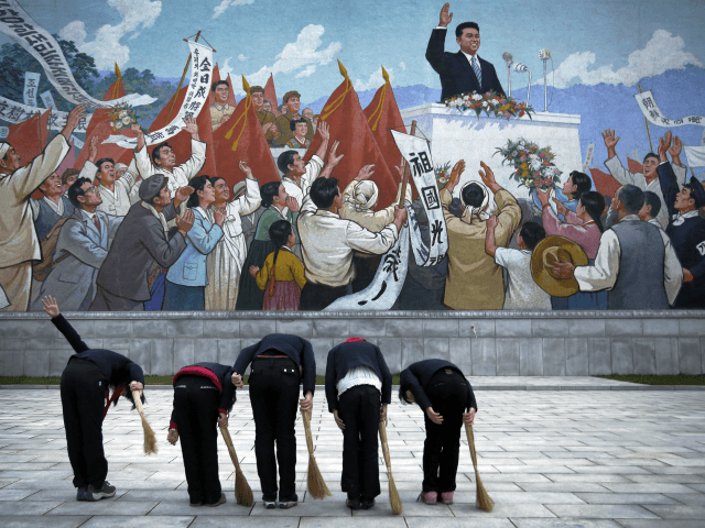 FILE - School girls holding brooms bow to pay their respects toward a mural that depicts the late North Korean leader Kim Il Sung delivering a speech, before sweeping the area surrounding the mural on Dec. 1, 2015, in Pyongyang, North Korea. (AP Photo/Wong Maye-E, File)