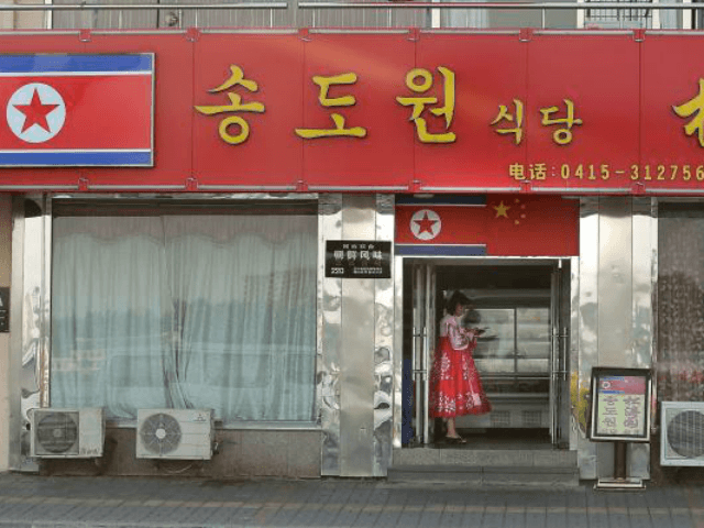 A North Korean woman and hostess stands outside Song Do Won in 2015. The restaurant recent