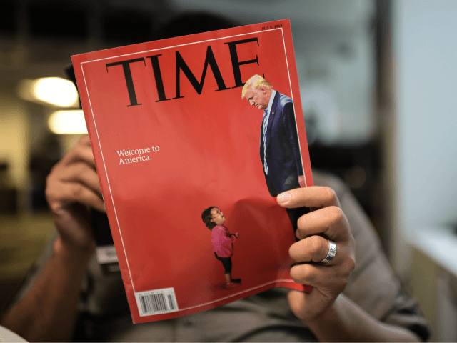 An AFP journalists reads a copy of Time Magazine with a front cover using a combination of