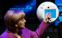 German Chancellor Angela Merkel interacts with CIMON, a "floating brain" device designed to aid astronauts aboard the International Space Station, while visiting an aerospace exhibit in Berlin in April 2018