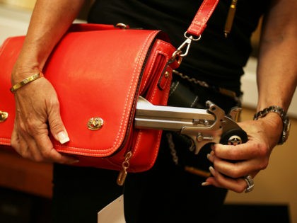 BOCA RATON, FL - OCTOBER 21: Susan Kushlin poses with a concealed-carry handbag that her company, Gun Girls, Inc., created for women that enjoy guns on October 21, 2013 in Boca Raton, Florida. Her line includes bullet jewelry, handbags, belts and custom logo apparel with some of the items priced …