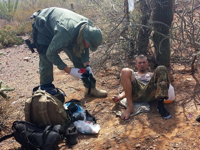 Border Patrol agent assists migrant suffering from dehydration in desert. (AP File Photo: