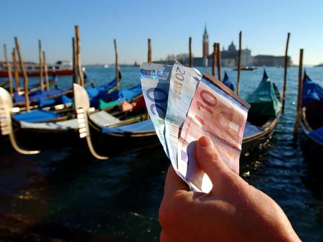 399185 03: A handful of new Euro notes are held in front of a row of Gondolas January 3, 2