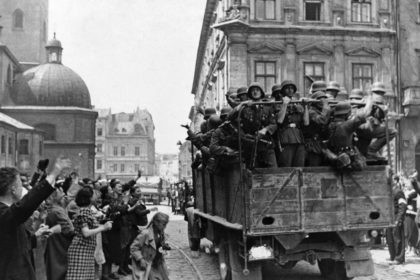 Inhabitants of the former Soviet-occupied Polish city of Lwow wave at a passing truckload of German soldiers as Nazi troops take over the city on July 2, 1941, according to the caption passed through German government censors. The city is now known as Lviv in Ukraine. (AP Photo)