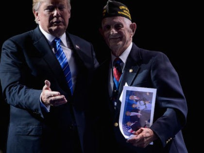 US President Donald Trump walks with WWII veteran Allen Q. Jones after signing a photo for