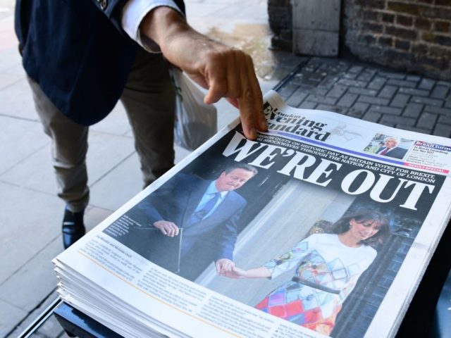 A man takes a copy of the London Evening Standard with the front page reporting the resign