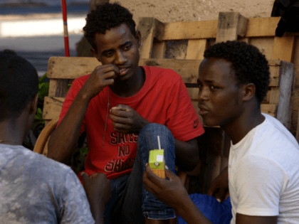 Migrants sit in the street of Via Cupa outside the former Baobab migrants reception centre