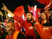 GettyImages-815139570 BERLIN, GERMANY - JULY 15: Pro-Erdogan Berlin Turks wave Turkish flags and one gives the hand sign of the ultra-nationalist Grey Wolves organization as they gather in front of the Turkish Embassy to commemorate the first anniversary of the failed coup in Turkey on July 15, 2017 in Berlin, Germany. …