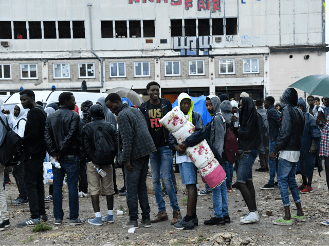 Migrants wait to board buses as police prepare the evacuation of a makeshift camp at Porte de la Chapelle, in the north of Paris, on August 18, 2017. More than a thousand migrants and refugees were evacuated on early August 18 from a makeshift camp that had been set up …