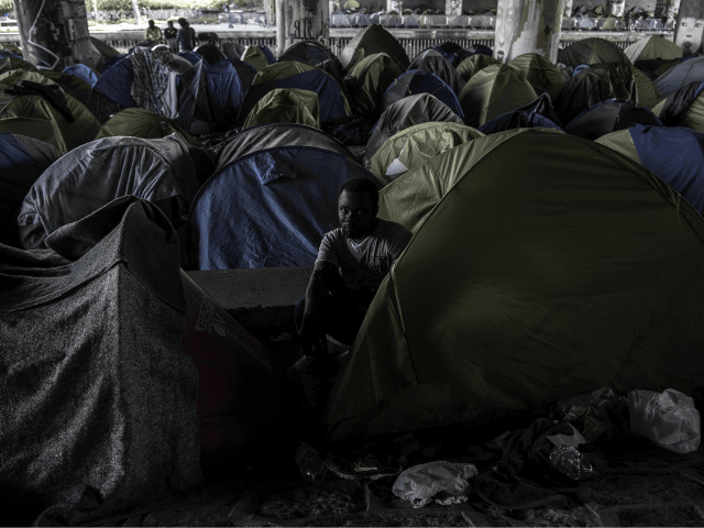 Burkina Faso's Aziz Porogo, a 28-year-old migrant, sits in his tent at a makeshift ca