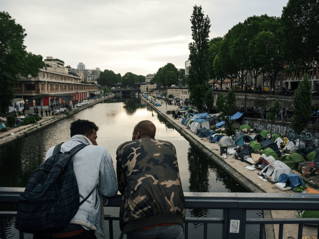 TOPSHOT - Men look at a makeshift camp during its evacuation by police, along the Canal de Saint-Martin at Quai de Valmy in Paris, on June 4, 2018. - More than 500 migrants and refugees were evacuated on early June 4, 2018 from a makeshift camp that had been set …