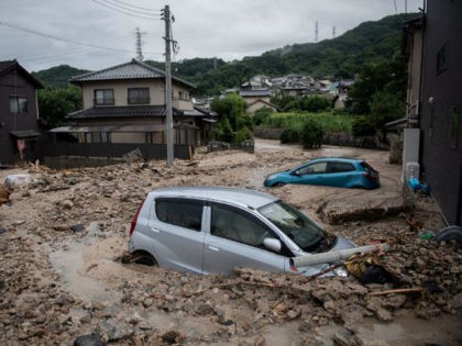 A picture shows cars trapped in the mud after floods in Saka, Hiroshima prefecture on July 8, 2018. - Japan's Prime Minister Shinzo Abe warned on July 8 of a 'race against time' to rescue flood victims as authorities issued new alerts over record rains that have killed at least …