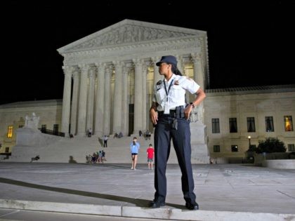 A Supreme Court Police officer stands watch as a protesters demonstrate in front of the Supreme Court in Washington, Monday, July 9, 2018, after President Donald Trump announced Judge Brett Kavanaugh as his Supreme Court nominee.