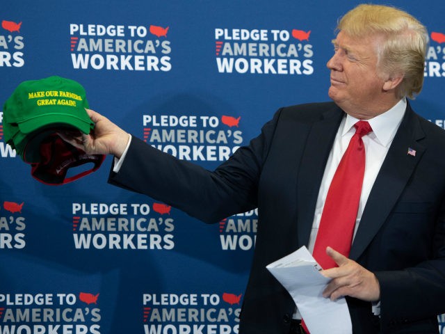 US President Donald Trump holds up 'Make Our Farmers Great Again!' hats as he arrives for a roundtable discussion on workforce development at Northeast Iowa Community College in Peosta, Iowa, July 26, 2018. (Photo by SAUL LOEB / AFP) (Photo credit should read SAUL LOEB/AFP/Getty Images)