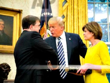 President Donald Trump, center, shakes hands with new Secretary of Veterans Affairs Robert Wilkie, left, following a ceremony in the Oval Office of the White House, Monday, July 30, 2018, in Washington. Also pictured is Wilkie's wife Julia, right.