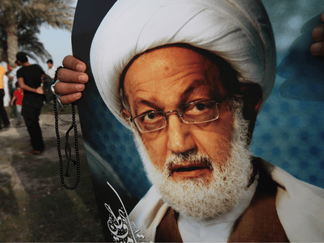 A Bahraini anti-government protester holds a poster of top Shiite cleric Sheik Isa Qassim