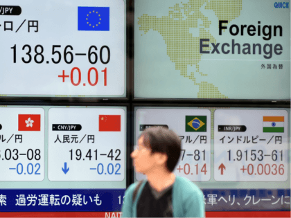 A pedestrian walks past a foreign exchange rate board, including the euro (top,L) and the